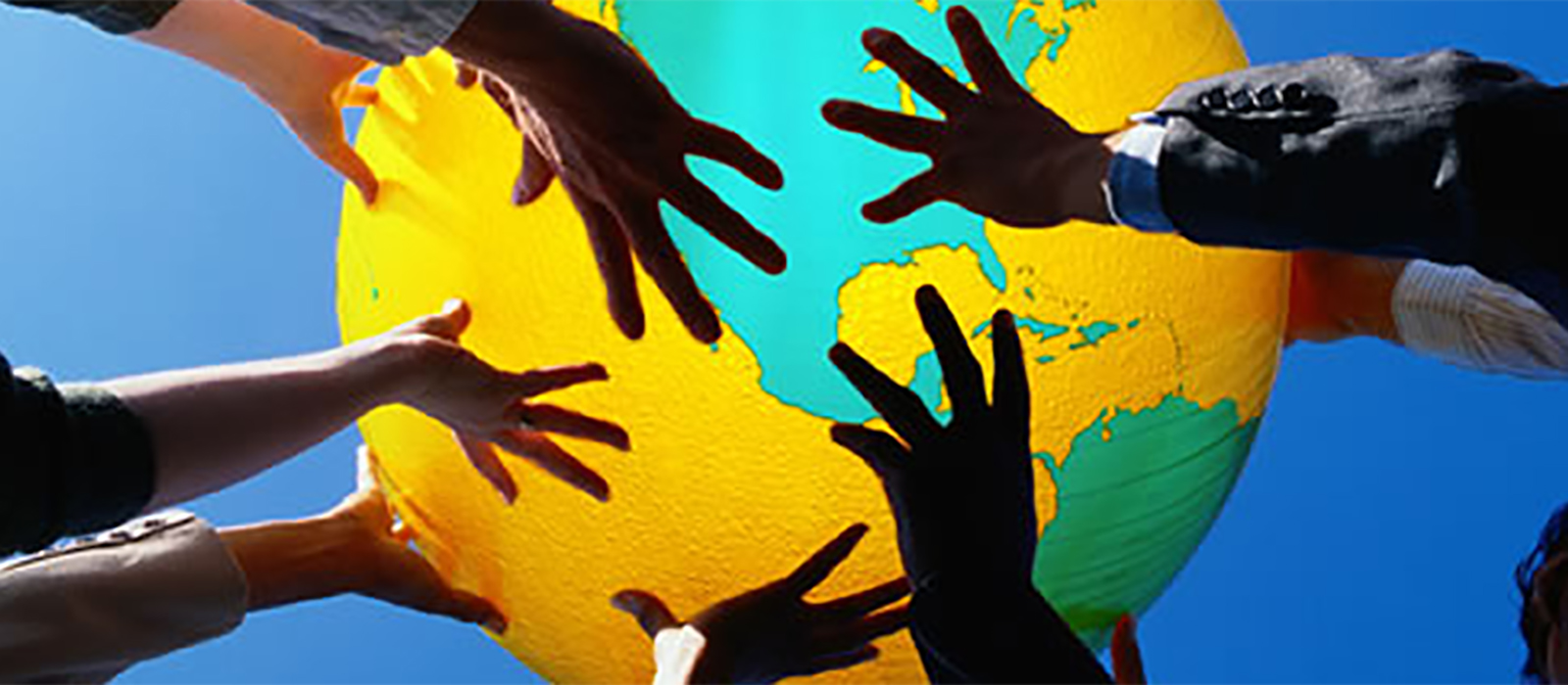 Several sets of hands holding up a globe